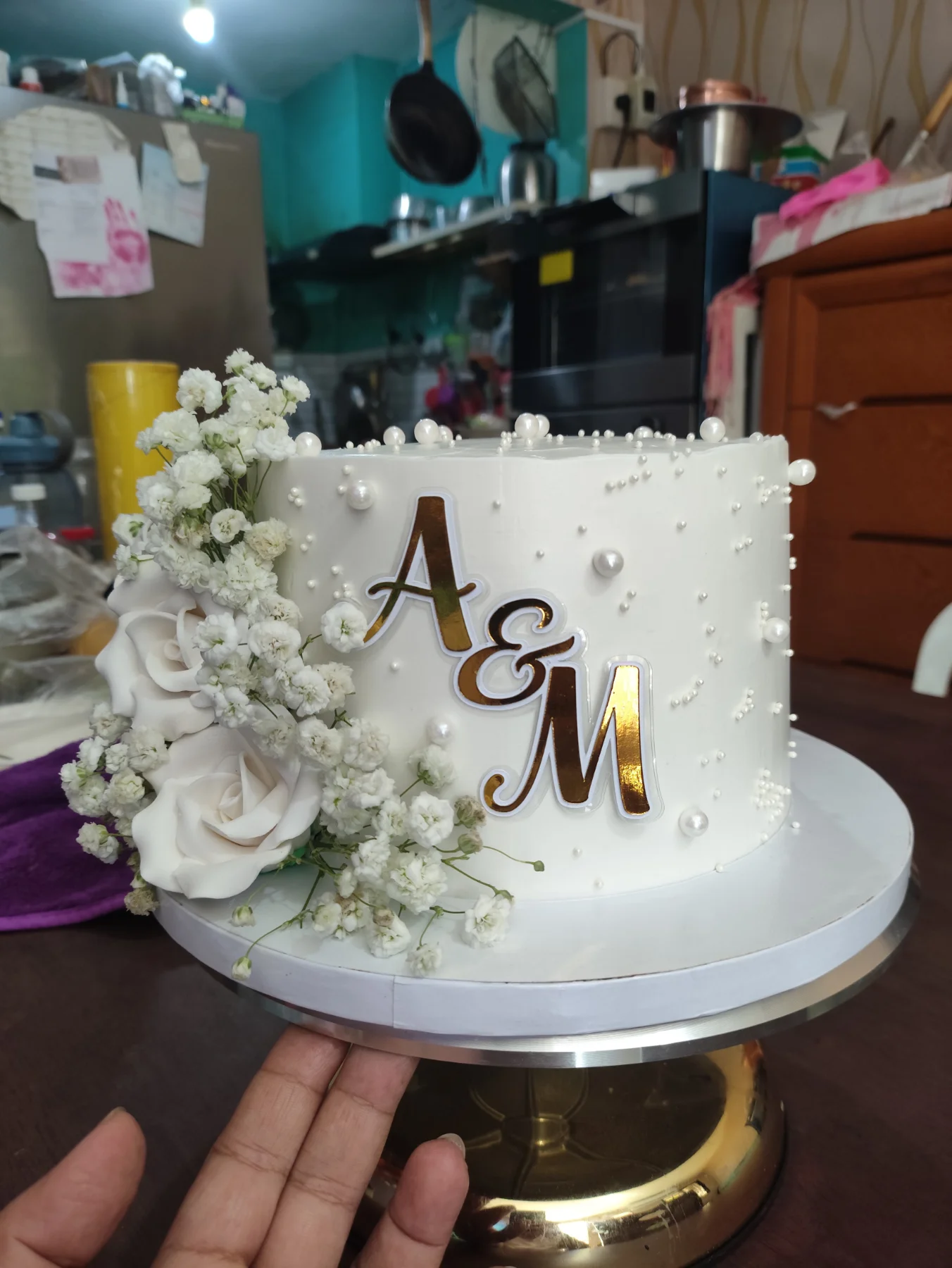 White minimalist cake with fresh white roses, baby's breath, and gold A&M initials