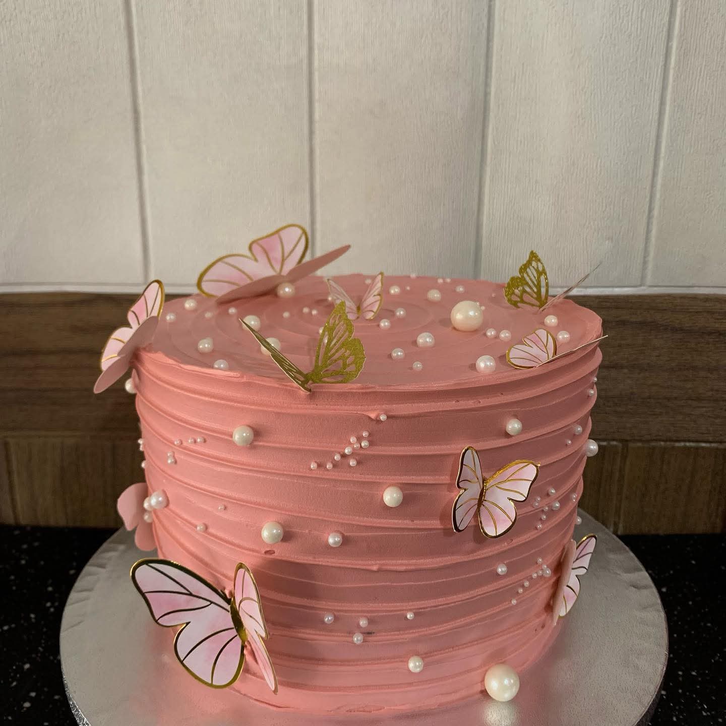 Pink textured icing cake decorated with pink and gold butterflies and white pearls