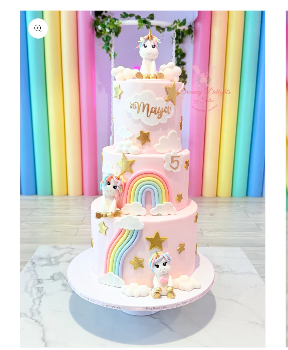 A three-tier light pink fondant cake decorated with edible fondant unicorns, rainbows, gold stars, and white clouds. A three-tier light pink fondant cake decorated with edible fondant unicorns, rainbows, gold stars, and white clouds.