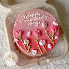 Pink bento cake with hand-piped pink roses and white buds, featuring a Happy Valentine's Day message in white icing.